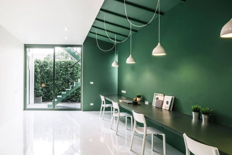 Sötétzöld árnyalatú falfestékkel festett modern étkezőfal függőlámpákkal és letisztult, természetközeli hangulattal