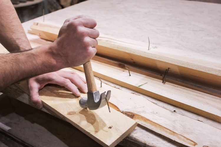 raklap deszkak bontasa kalapaccsal szeg eltavolitas kozben faanyag ujrahasznositasahoz DIY kerti projektekhez magasagyas vagy butorkeszites elokeszitesehez