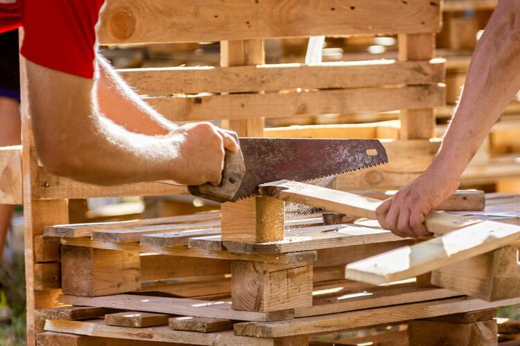 raklapbutor keszitese kozben faanyag fureszelese keziszerszammal ujrahasznositott raklapokbol kerti butor epiteshez es diy faipari projektekhez